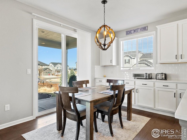 dining area featuring a toaster, baseboards, dark wood-style flooring, and a notable chandelier