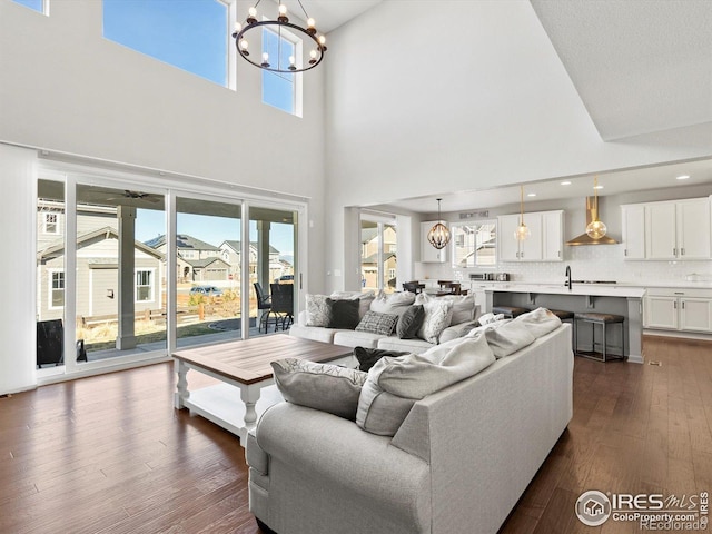 living area with an inviting chandelier, plenty of natural light, and a towering ceiling