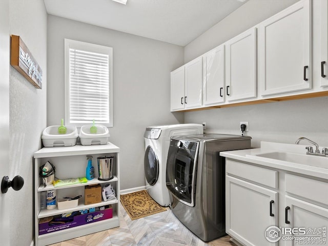 washroom with baseboards, a sink, cabinet space, and washer and dryer