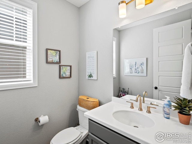 bathroom featuring toilet, a wealth of natural light, and vanity