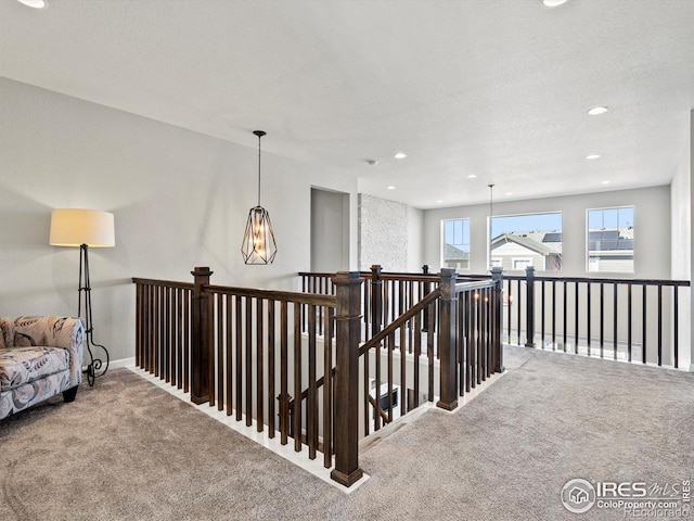 hall with carpet floors, recessed lighting, an inviting chandelier, and an upstairs landing