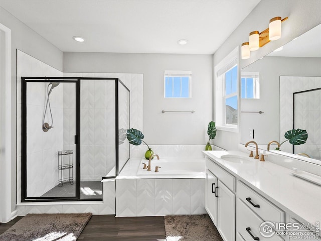 full bath featuring vanity, a garden tub, a shower stall, and wood finished floors