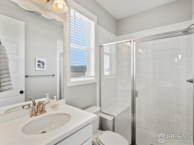 full bathroom featuring vanity, toilet, visible vents, and a stall shower