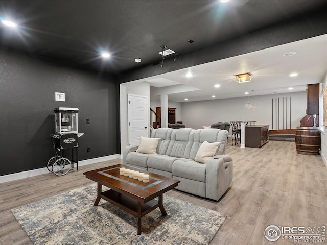 living room featuring stairs, recessed lighting, baseboards, and light wood finished floors