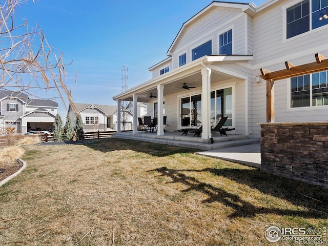 back of property with a lawn, a ceiling fan, and a patio area
