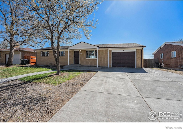 ranch-style house with a garage, fence, cooling unit, brick siding, and driveway
