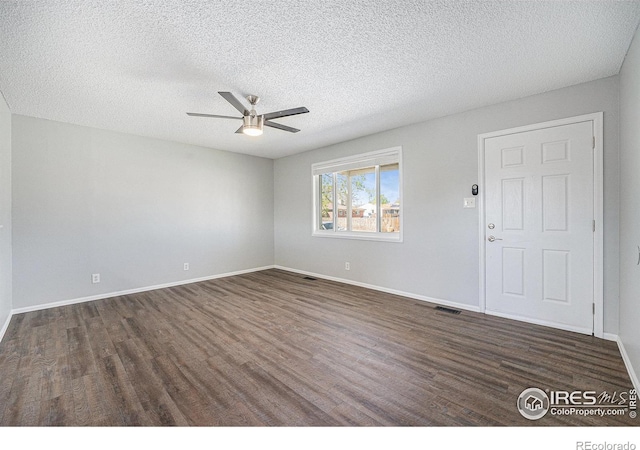 spare room featuring baseboards, dark wood finished floors, and ceiling fan