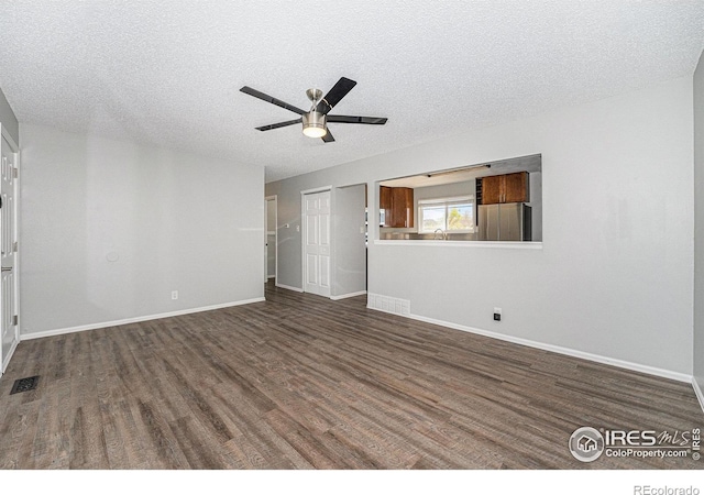 unfurnished living room with visible vents, baseboards, dark wood-style floors, a textured ceiling, and a ceiling fan
