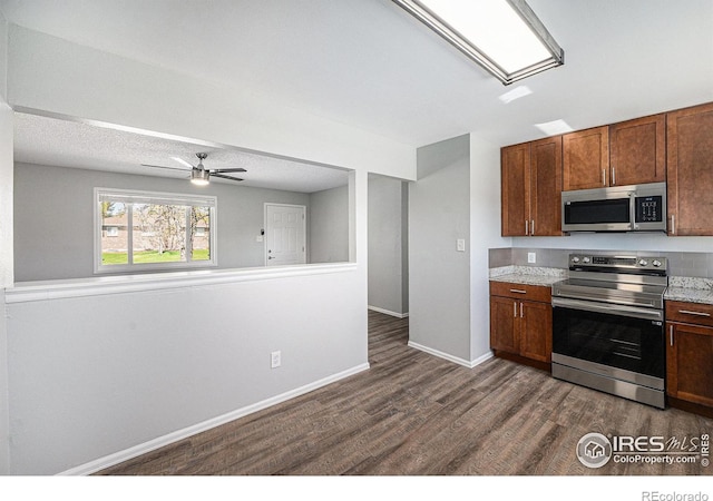 kitchen with brown cabinets, dark wood-style flooring, ceiling fan, appliances with stainless steel finishes, and baseboards