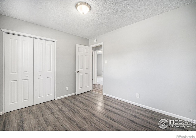 unfurnished bedroom featuring a closet, baseboards, a textured ceiling, and wood finished floors