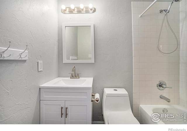 bathroom with vanity, shower / bathing tub combination, a textured wall, and toilet