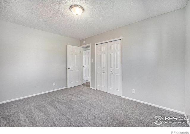 unfurnished bedroom featuring baseboards, a textured ceiling, carpet floors, and a closet