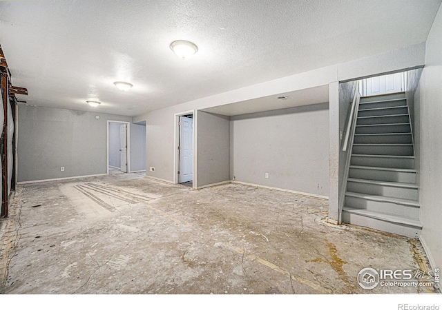 finished basement with stairway and a textured ceiling