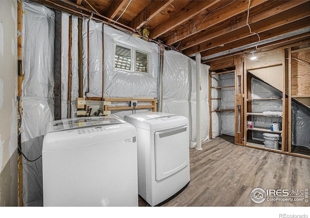 clothes washing area with laundry area, wood finished floors, and washing machine and clothes dryer
