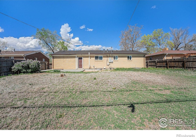 rear view of house with a yard, brick siding, and a fenced backyard