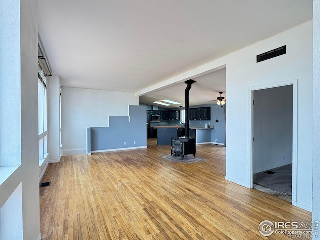 115 Arapaho Ridge Rd, Livermore, CO 80536 - unfurnished living room with ceiling fan, visible vents, a wood stove, baseboards, and light wood finished floors