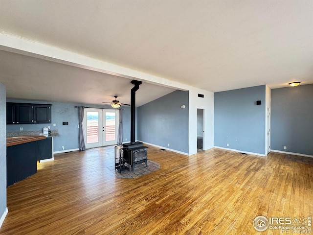 115 Arapaho Ridge Rd, Livermore, CO 80536 - unfurnished living room featuring baseboards, ceiling fan, a wood stove, and light wood-type flooring
