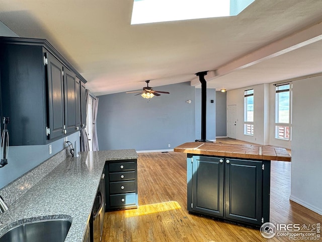 115 Arapaho Ridge Rd, Livermore, CO 80536 - kitchen featuring a wood stove, a peninsula, light wood-style floors, open floor plan, and a ceiling fan