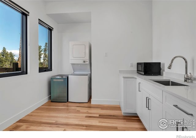 11 Juneau Cir, Nederland, CO 80466 - laundry room with a sink, baseboards, cabinet space, and stacked washing maching and dryer