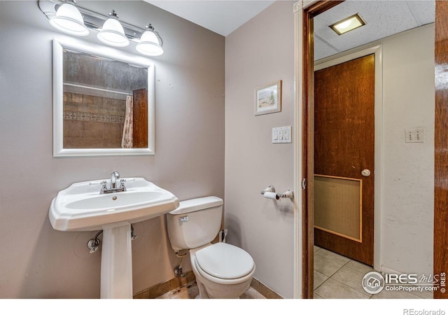 bathroom with toilet, tile patterned flooring, and baseboards