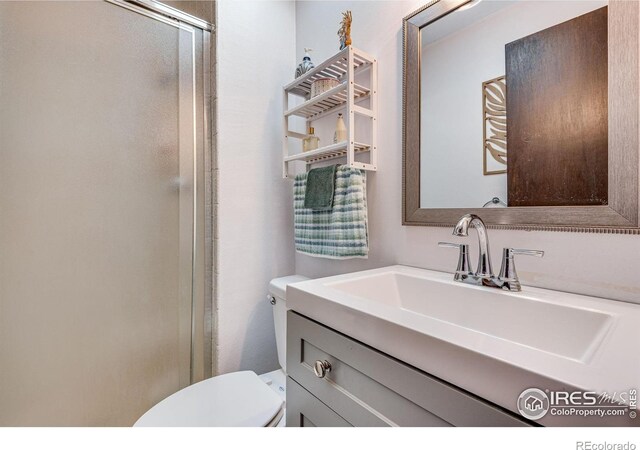 full bathroom featuring toilet, a shower stall, and vanity