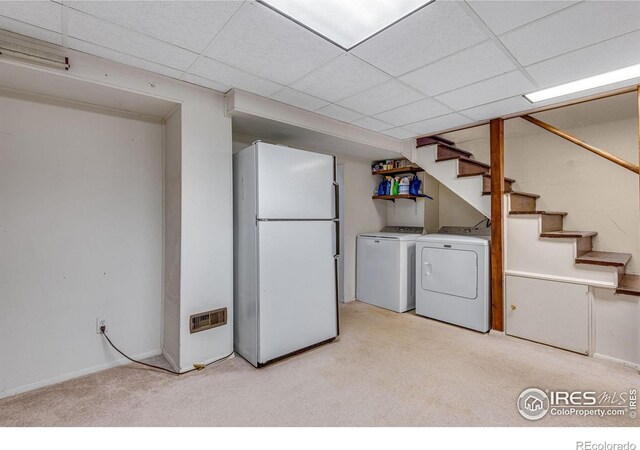 washroom featuring washing machine and clothes dryer, light carpet, and baseboards