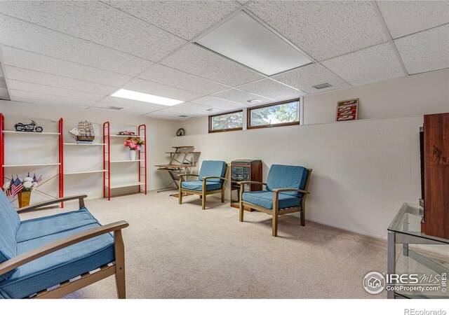 sitting room featuring carpet floors and a drop ceiling
