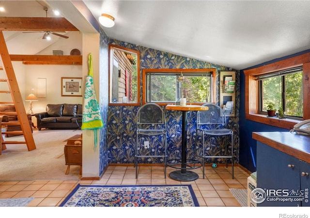 tiled dining area featuring ceiling fan, carpet flooring, wallpapered walls, and lofted ceiling