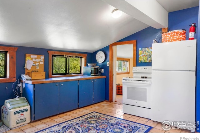 kitchen with light tile patterned floors, blue cabinets, white appliances, and lofted ceiling