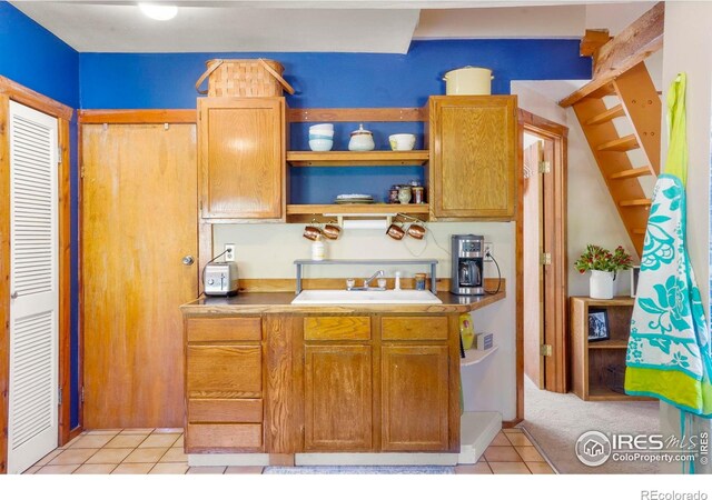 kitchen with a sink, open shelves, light tile patterned floors, and light countertops