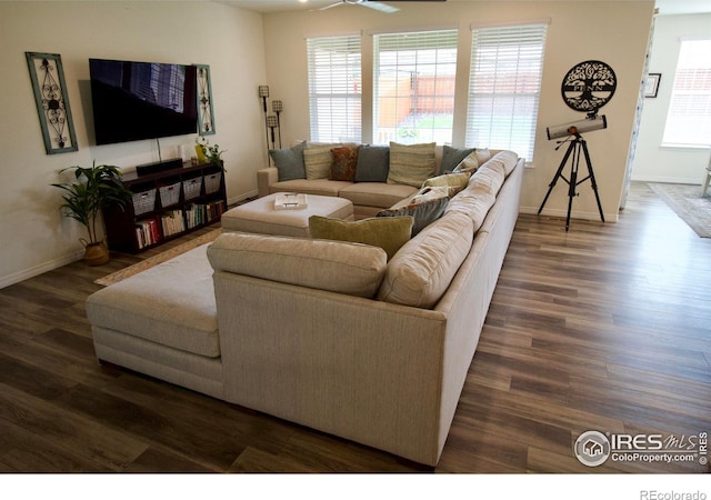 living area featuring baseboards, a ceiling fan, and dark wood-style floors