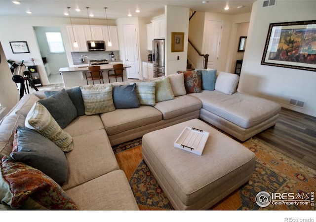 living area with stairs, recessed lighting, visible vents, and wood finished floors