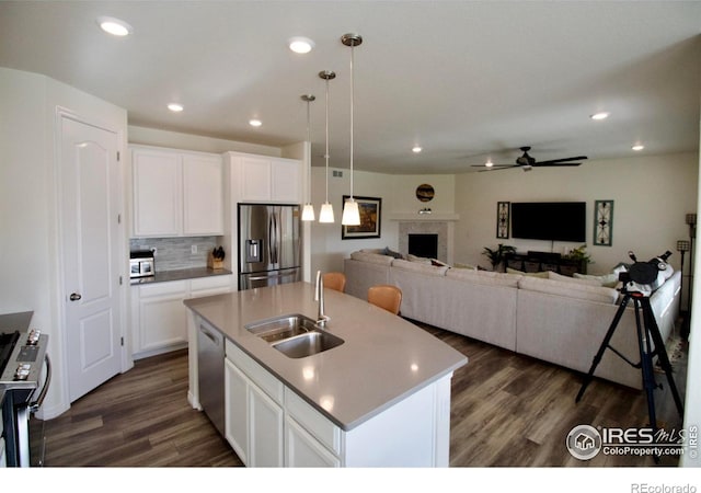 kitchen with a ceiling fan, dark wood-style flooring, a fireplace, a sink, and stainless steel appliances