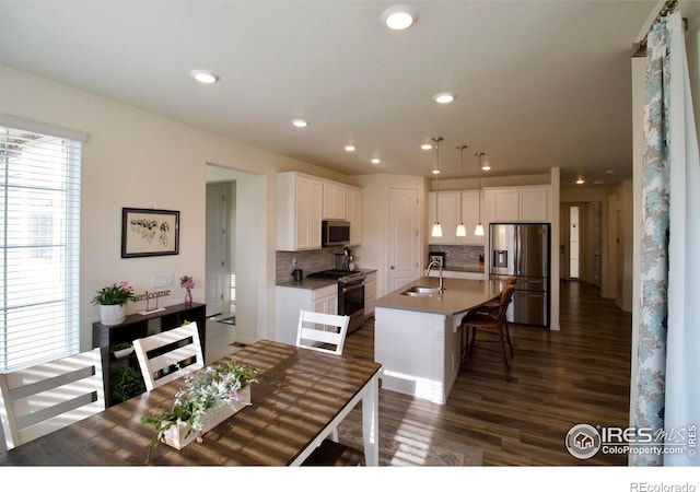 kitchen featuring decorative backsplash, white cabinets, a sink, dark wood finished floors, and appliances with stainless steel finishes