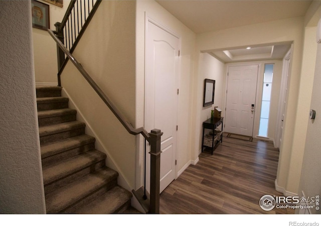 foyer with baseboards, stairs, and dark wood-style flooring