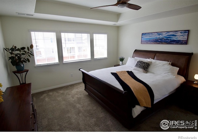 bedroom with carpet flooring, a raised ceiling, a ceiling fan, baseboards, and visible vents