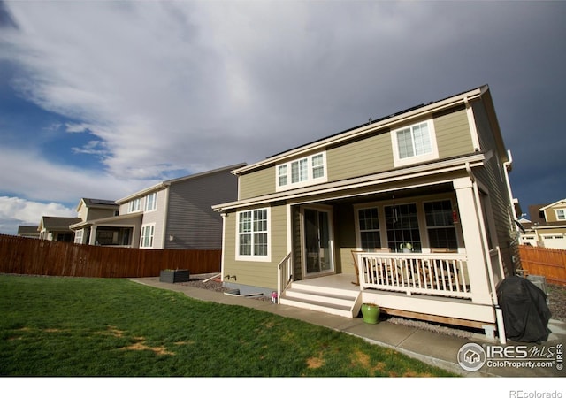 rear view of property with a porch, fence, and a yard
