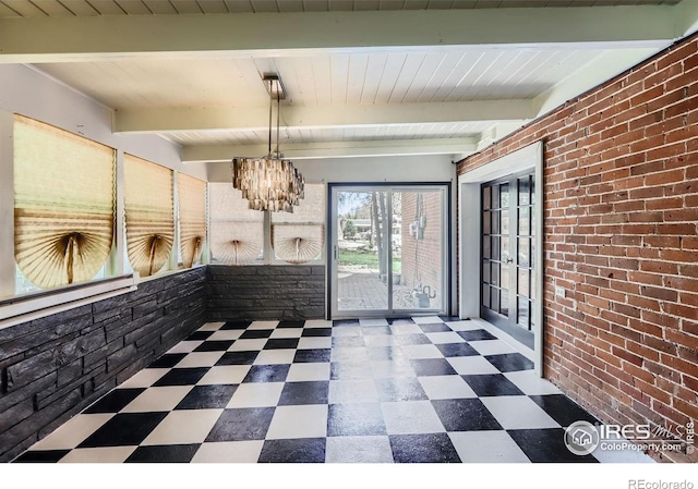 unfurnished dining area with brick wall, beam ceiling, tile patterned floors, a baseboard radiator, and an inviting chandelier