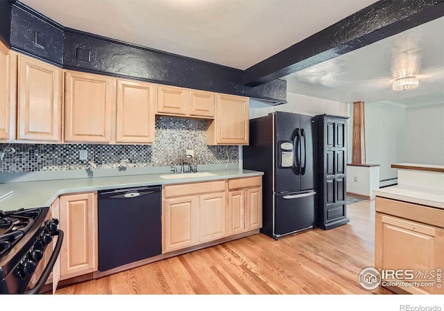 kitchen with a sink, light brown cabinetry, and black appliances