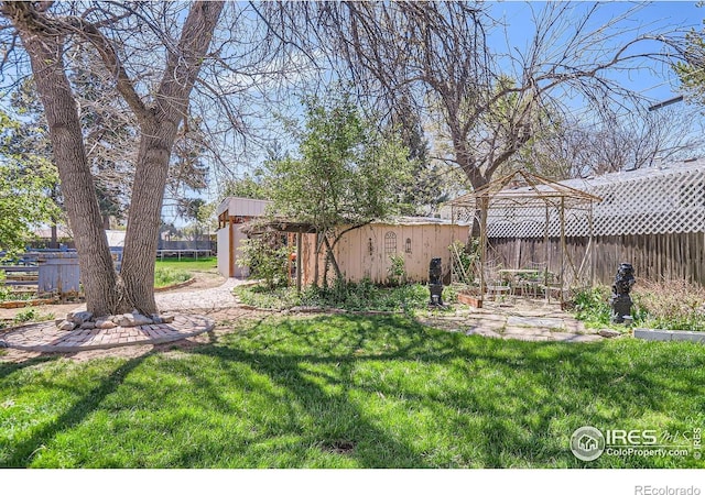 view of yard featuring a gazebo, fence, an outdoor structure, and a patio area