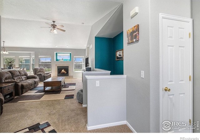 living room with carpet floors, ceiling fan, a lit fireplace, and a wealth of natural light
