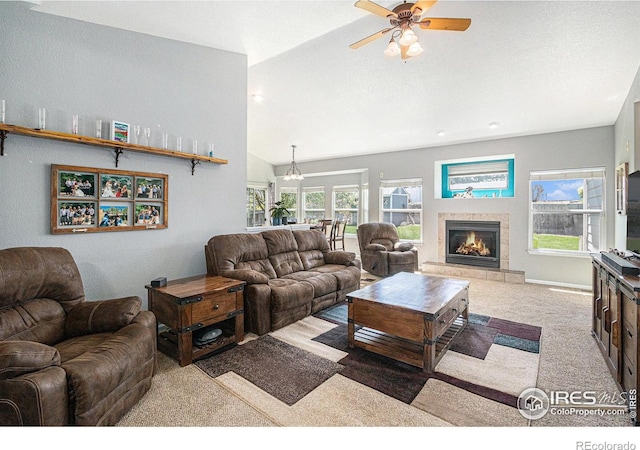 carpeted living area featuring a tiled fireplace, a ceiling fan, and lofted ceiling