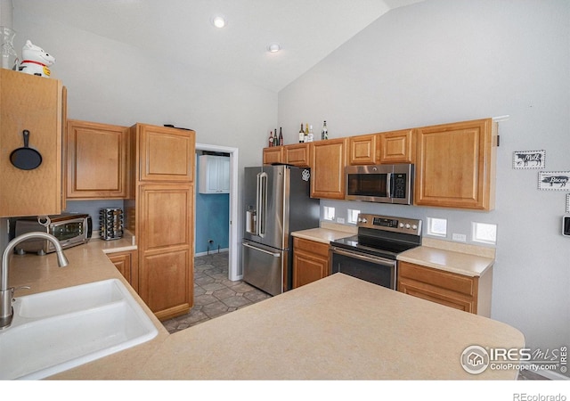 kitchen featuring light countertops, high vaulted ceiling, appliances with stainless steel finishes, and a sink