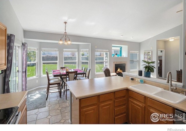 kitchen with electric range, a warm lit fireplace, light countertops, a chandelier, and a sink