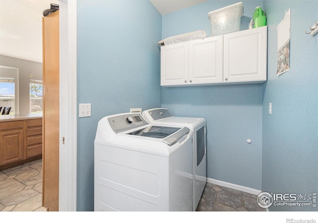 laundry area with cabinet space, separate washer and dryer, and baseboards