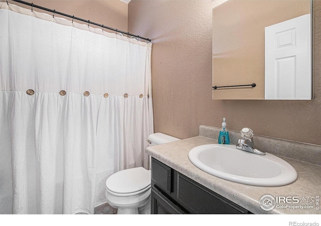 full bath with toilet, a textured wall, a shower with curtain, and vanity