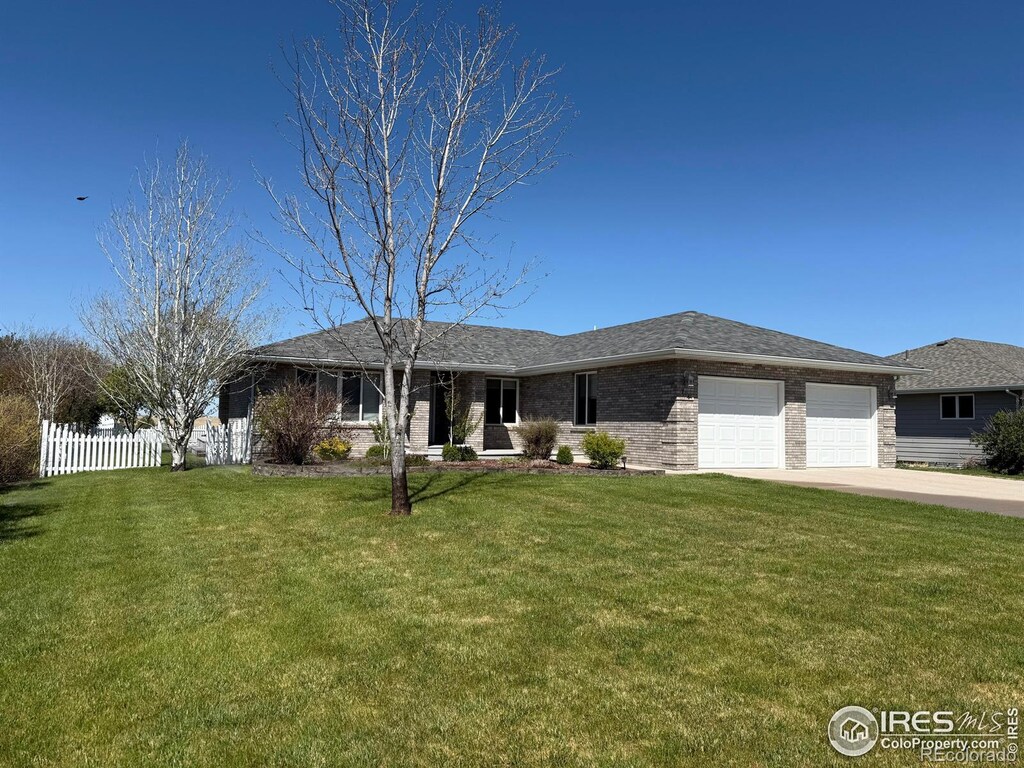 714 S Wynona Ave, Holyoke, CO 80734 - view of front of home featuring fence, an attached garage, concrete driveway, and a front yard
