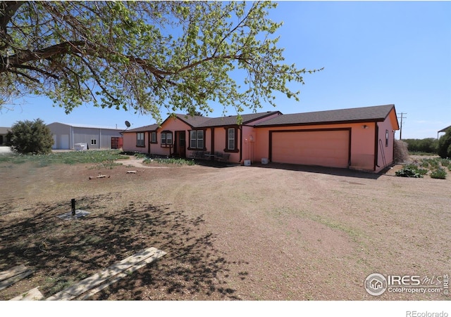 ranch-style house featuring dirt driveway and an attached garage