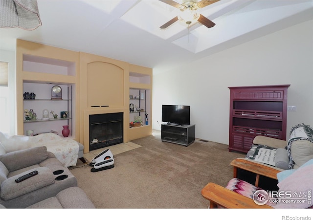 living room featuring ceiling fan, light colored carpet, a fireplace with flush hearth, and a skylight