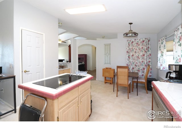 kitchen with arched walkways, black electric cooktop, light floors, light brown cabinets, and tile counters